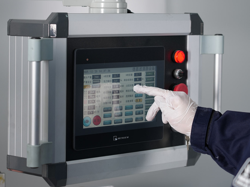 Worker operating the HMI touch screen control panel of an automated air filter production machine